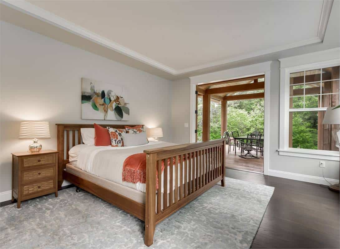 Primary bedroom with private deck access, a tray ceiling, and a wooden bed over a gray area rug.