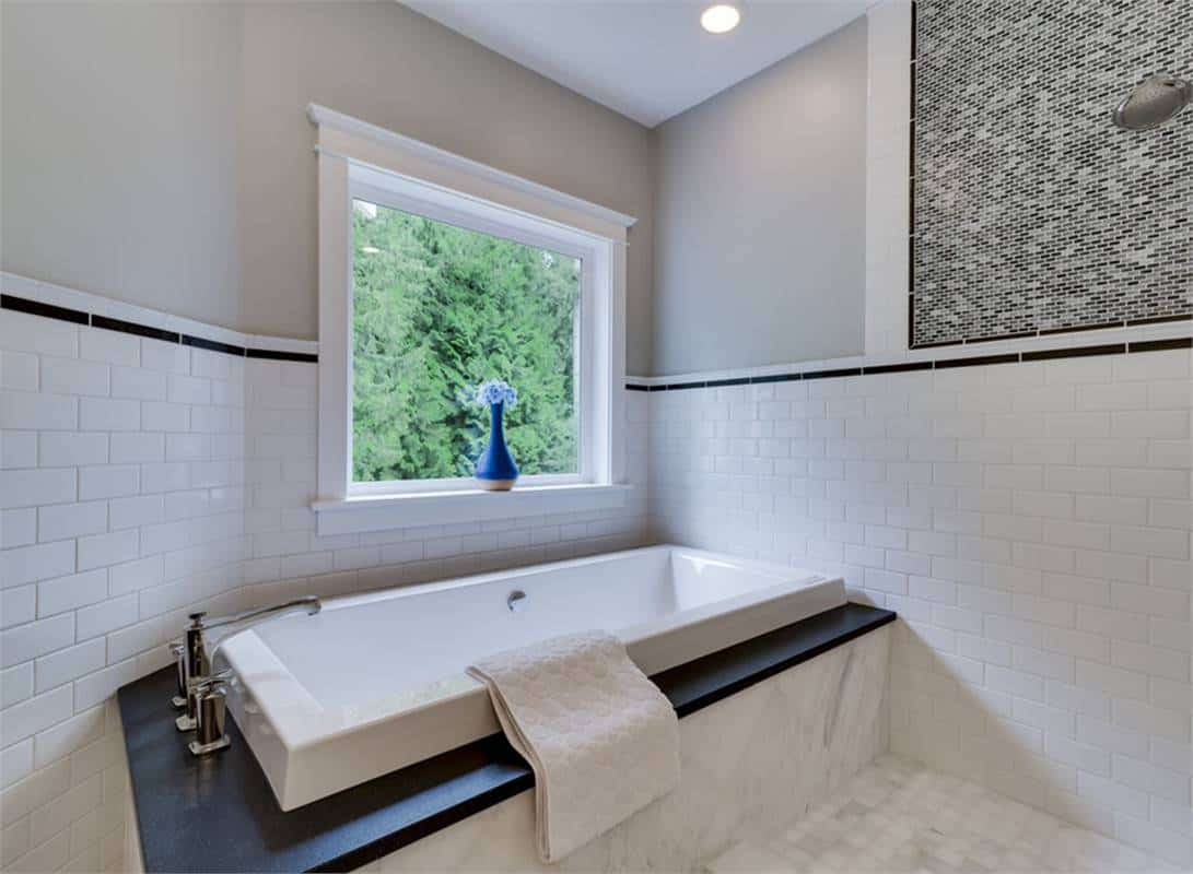 Primary bathroom with a drop-in bathtub illuminated by a picture window.