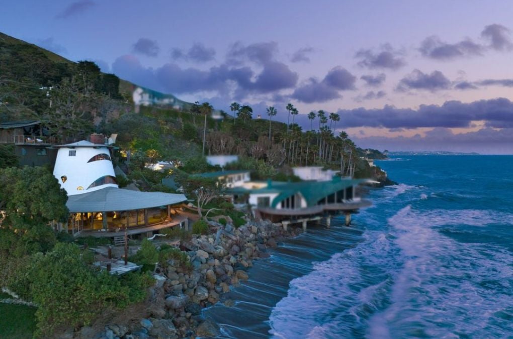 An aerial view of a house on a cliff overlooking the ocean