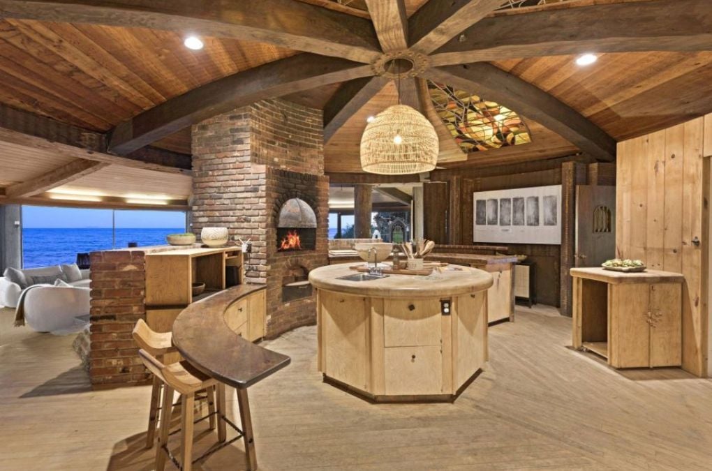 A kitchen with a fireplace and a wooden center island.