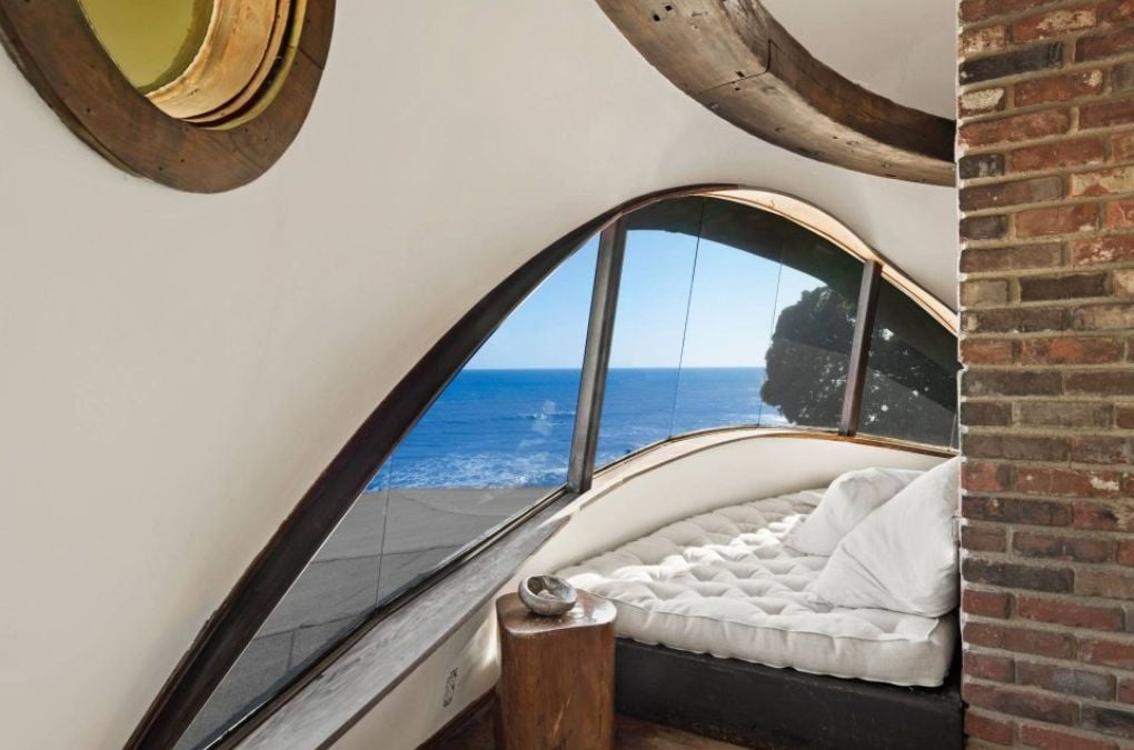 a bedroom with a curved window and a view of the ocean.