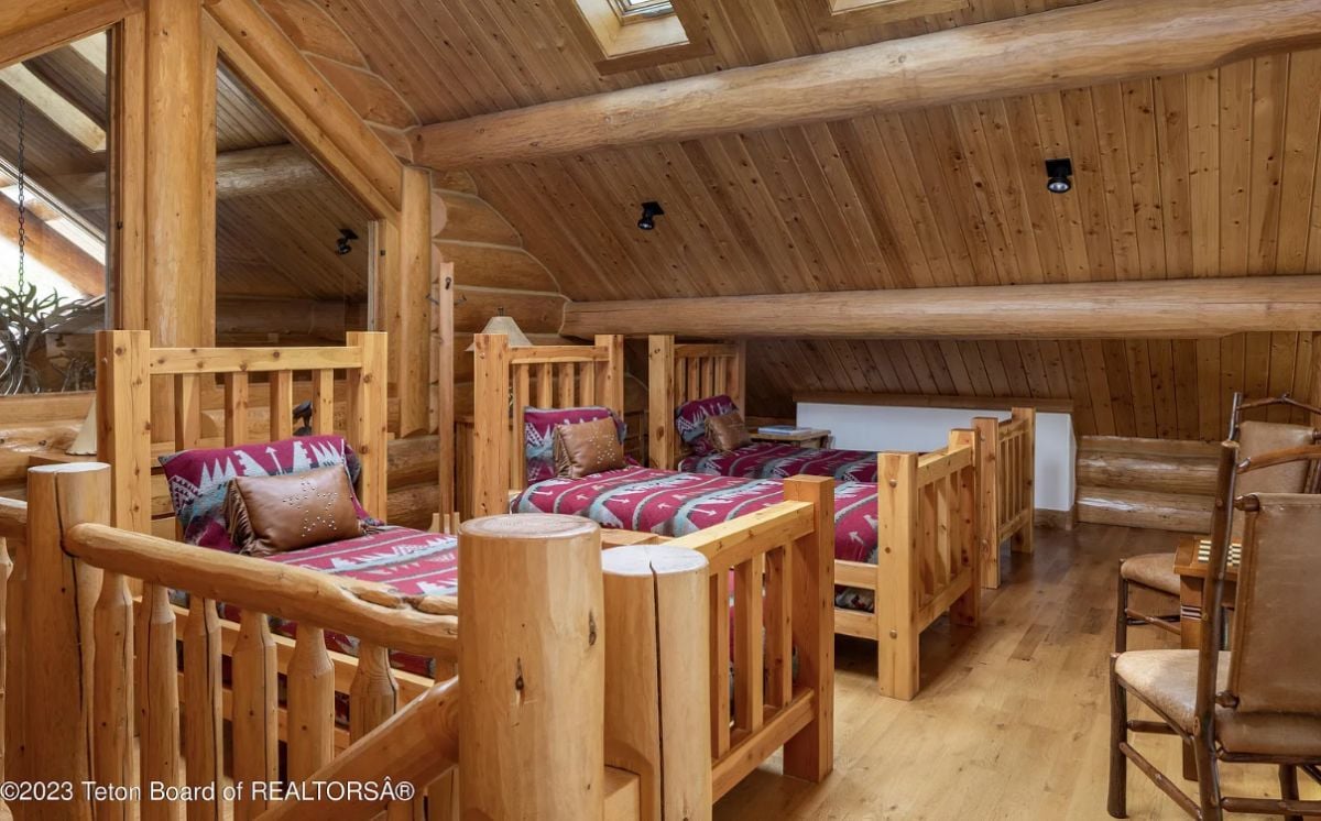 Bedroom with three beds, wooden walls and a wooden ceiling.