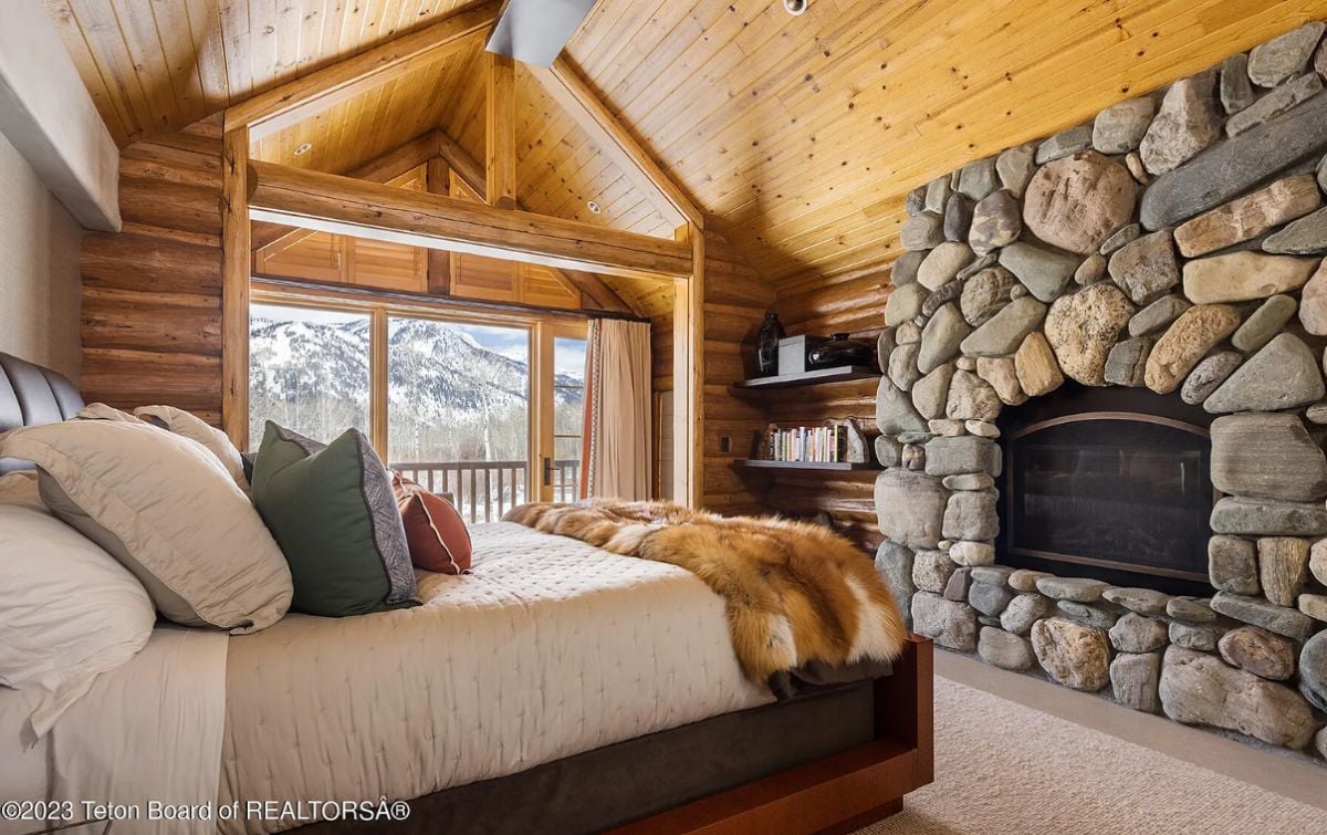 Bedroom with a fireplace, glass doors and a view of the mountains.