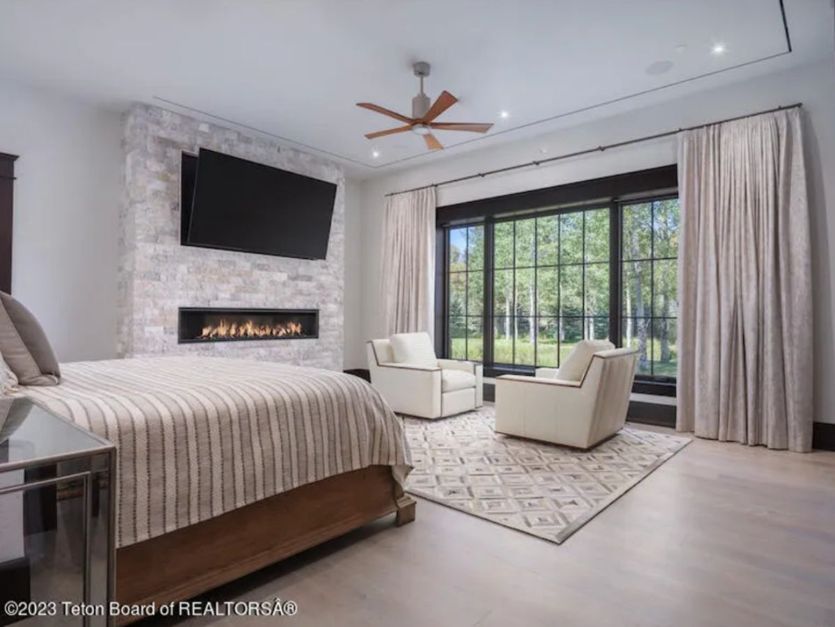 Bedroom with custom lighting, a TV and a fireplace.