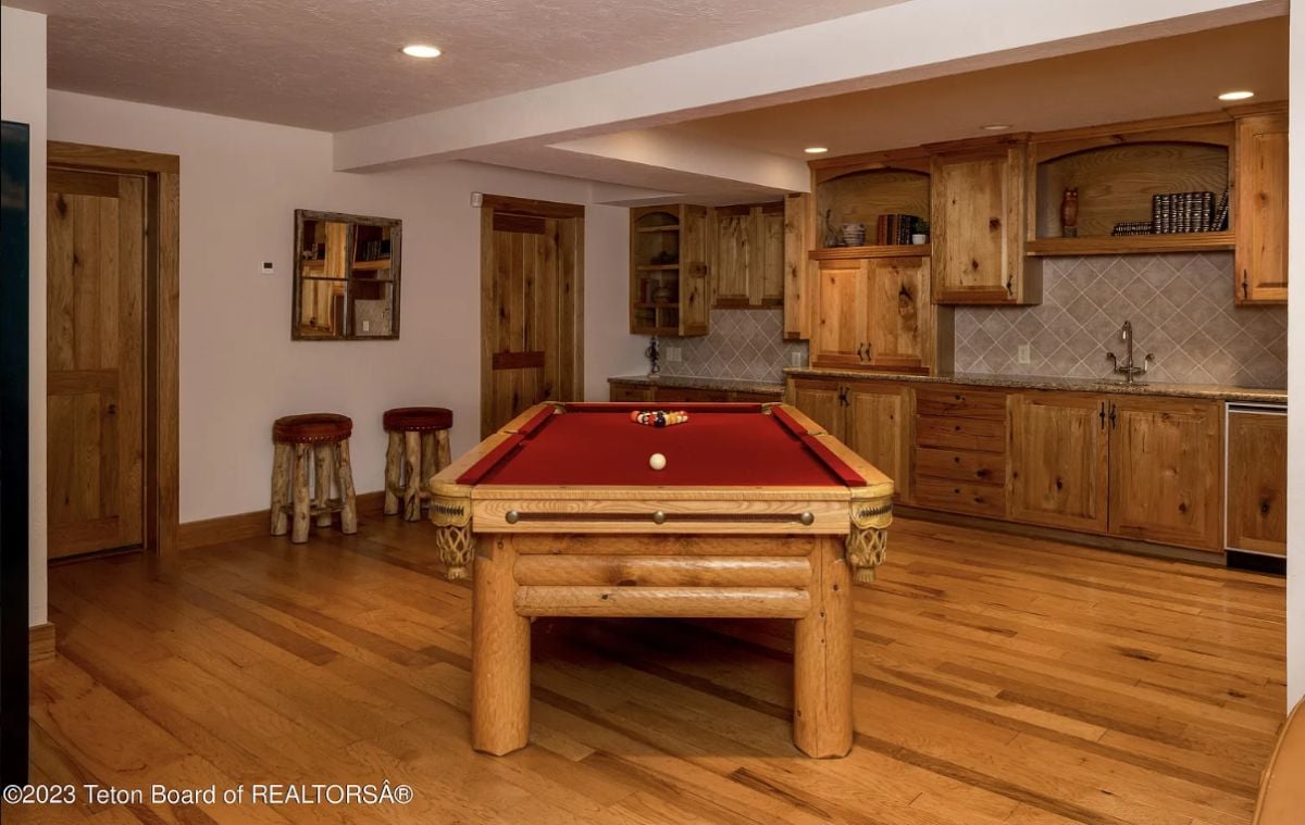 Billiards room with custom lighting, a sink, and wooden cabinets.