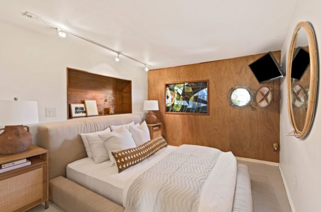A bedroom in the boat house with a painting and a TV.