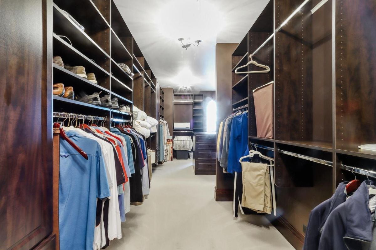 Walk-in closet with wooden shelves and drawers.