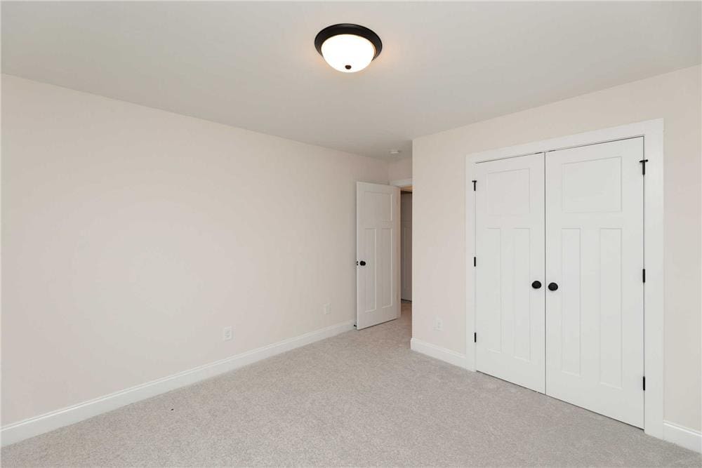 Secondary bedroom with carpet flooring and a built-in wardrobe with double doors.