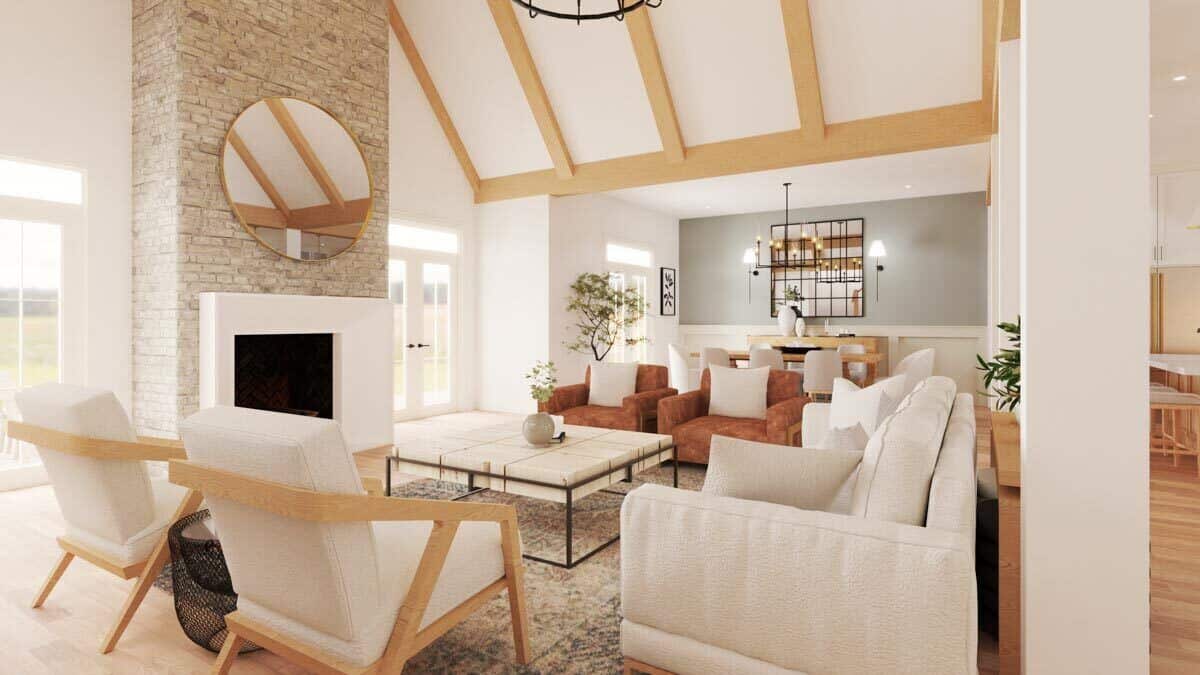 Great room with white and brown seats, a metal coffee table, and a fireplace topped with a round mirror.