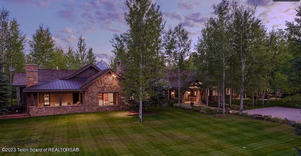 Backyard of the house with a large green lawn.