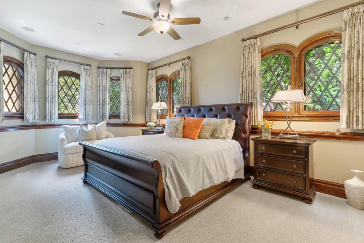 Bedroom with carpet flooring, a large bed, and a ceiling fan.