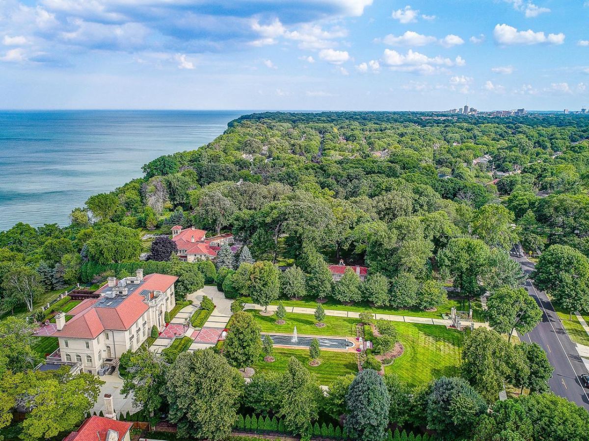 Aerial view of the mansion with a lake in the background.