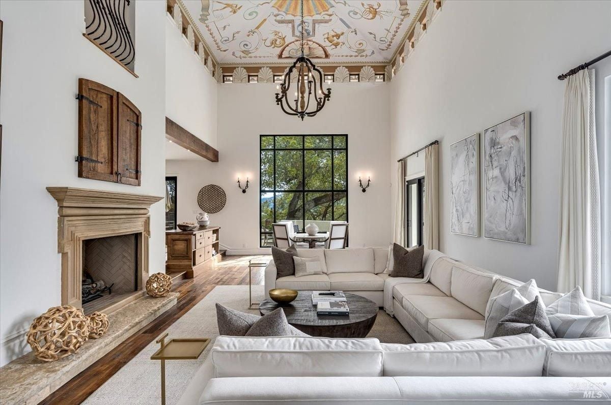 Living room with couches, fireplace and a chandelier.