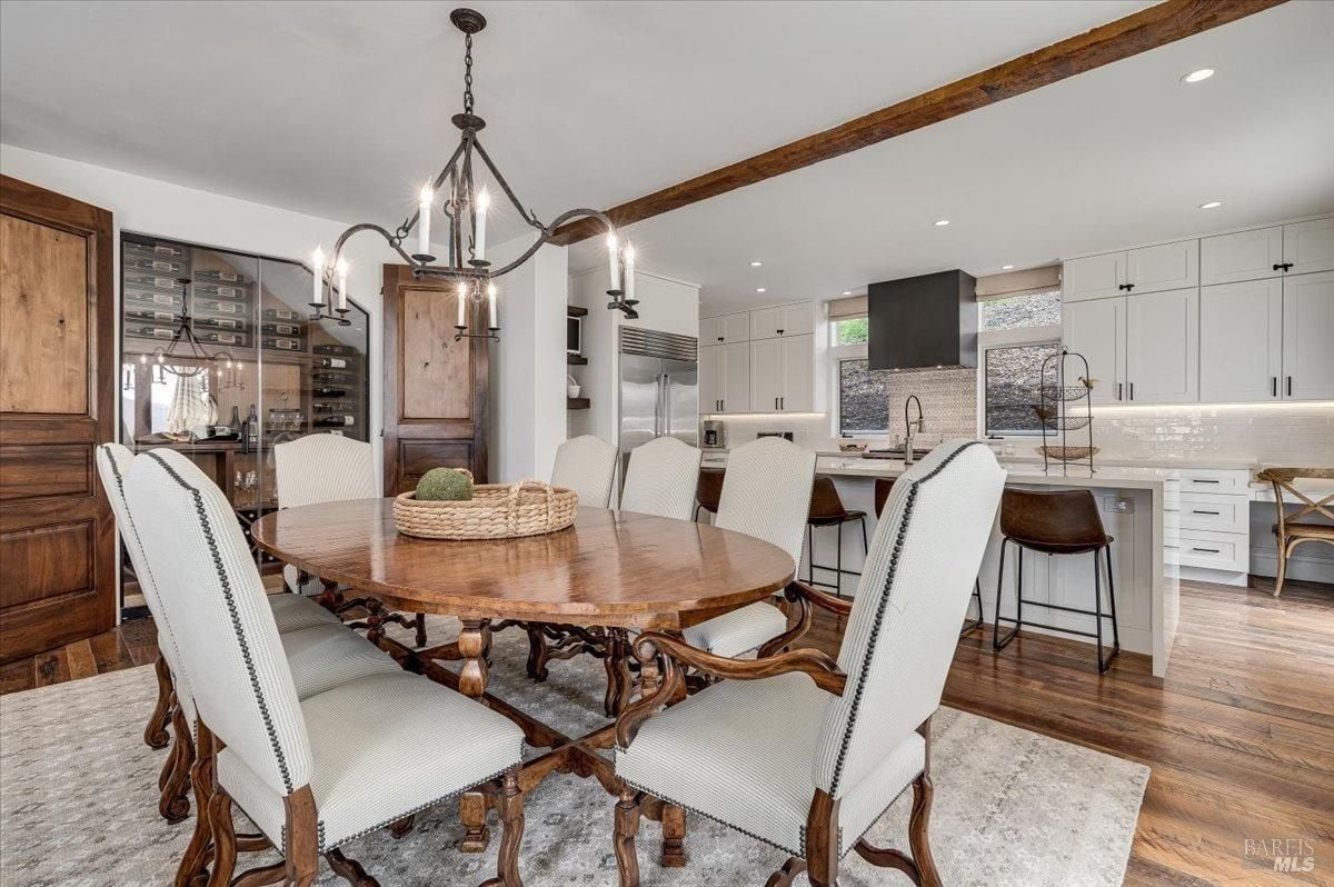 Dining room with chandelier, a large table and wood flooring.
