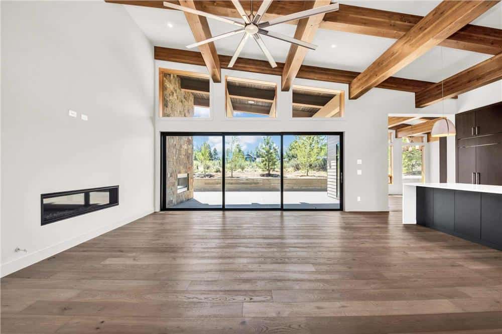 Great room with a large fireplace and a shed ceiling framed with exposed wood beams.