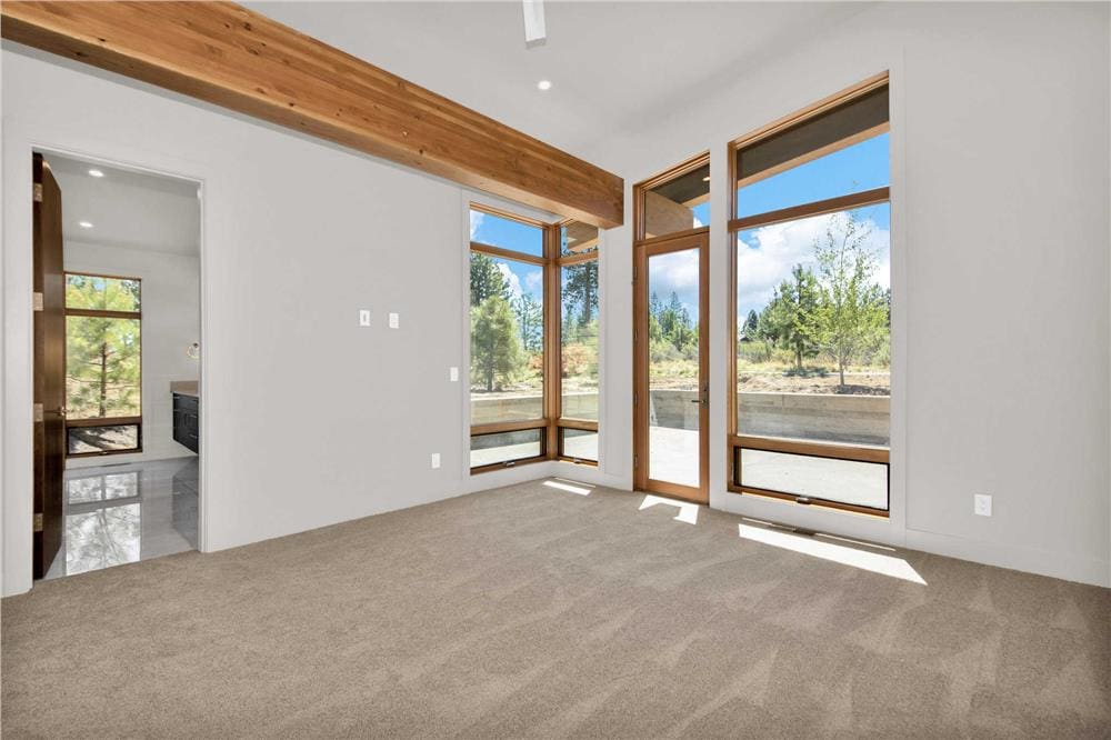 Primary bedroom with carpeted floor, an ensuite bath, and outdoor access.