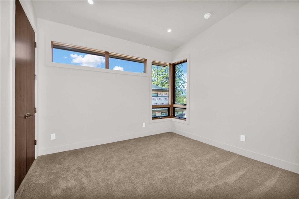 Secondary bedroom with corner and clerestory windows, a carpeted floor, and a built-in closet.