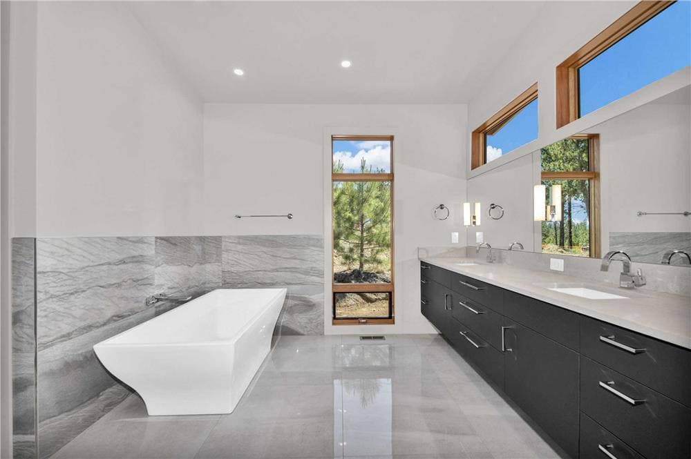 Primary bathroom with a soaking tub and a dual sink vanity topped with clerestory windows.