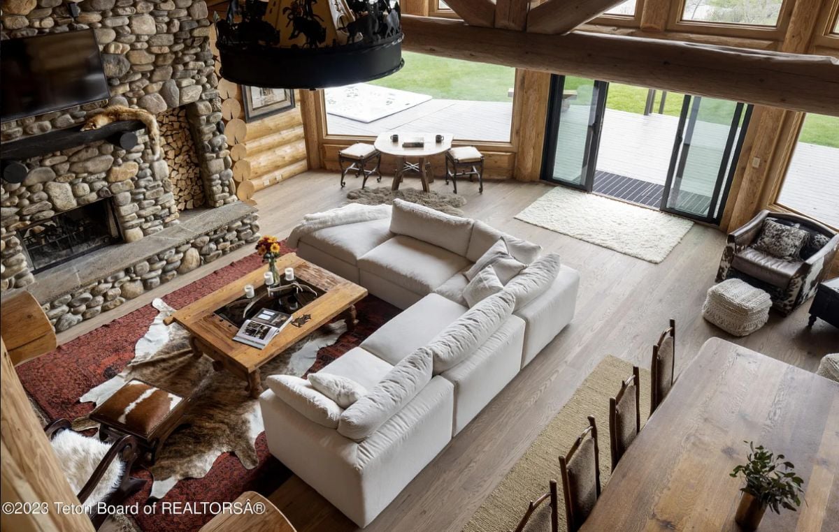 Living room with couches, wooden floors, a large rug, and a fireplace.