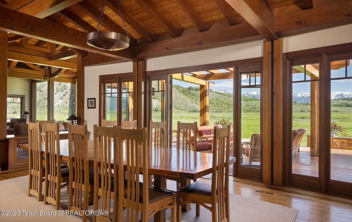 Dining room with vaulted ceiling, wooden floors, a large rug and glass doors.