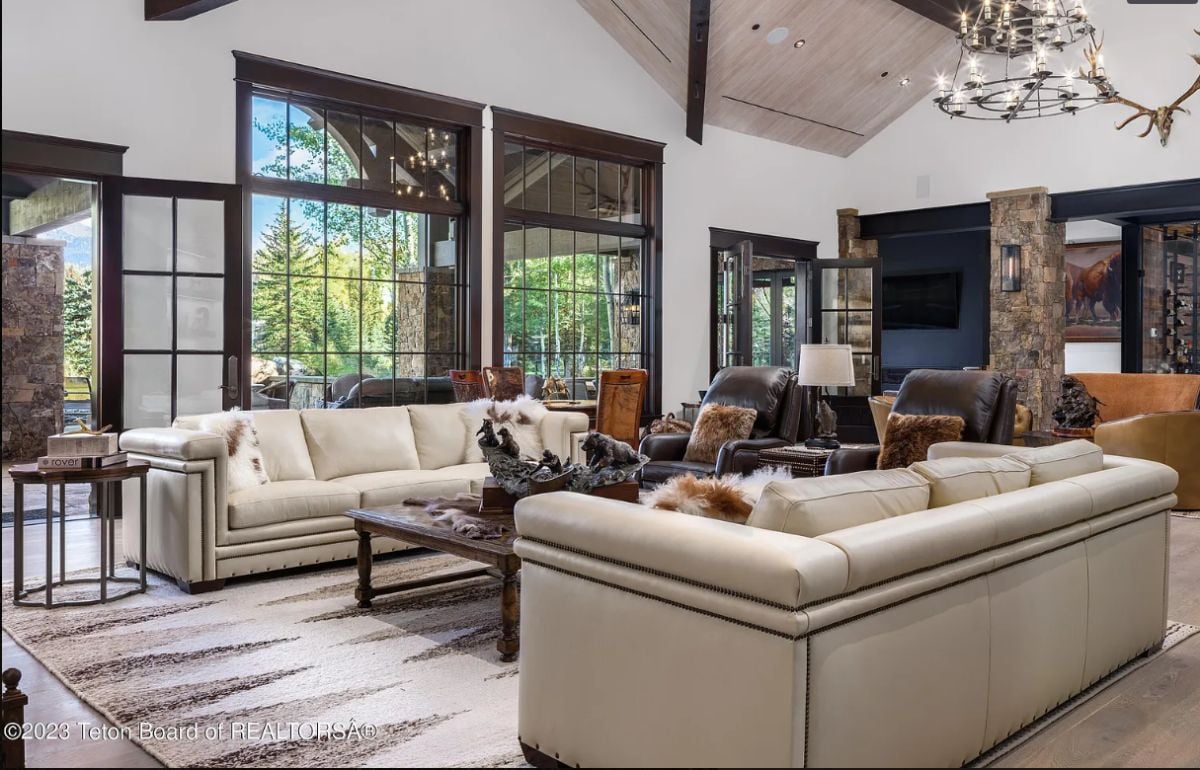 Living room with a chandelier, couches, glass doors, and glass windows.