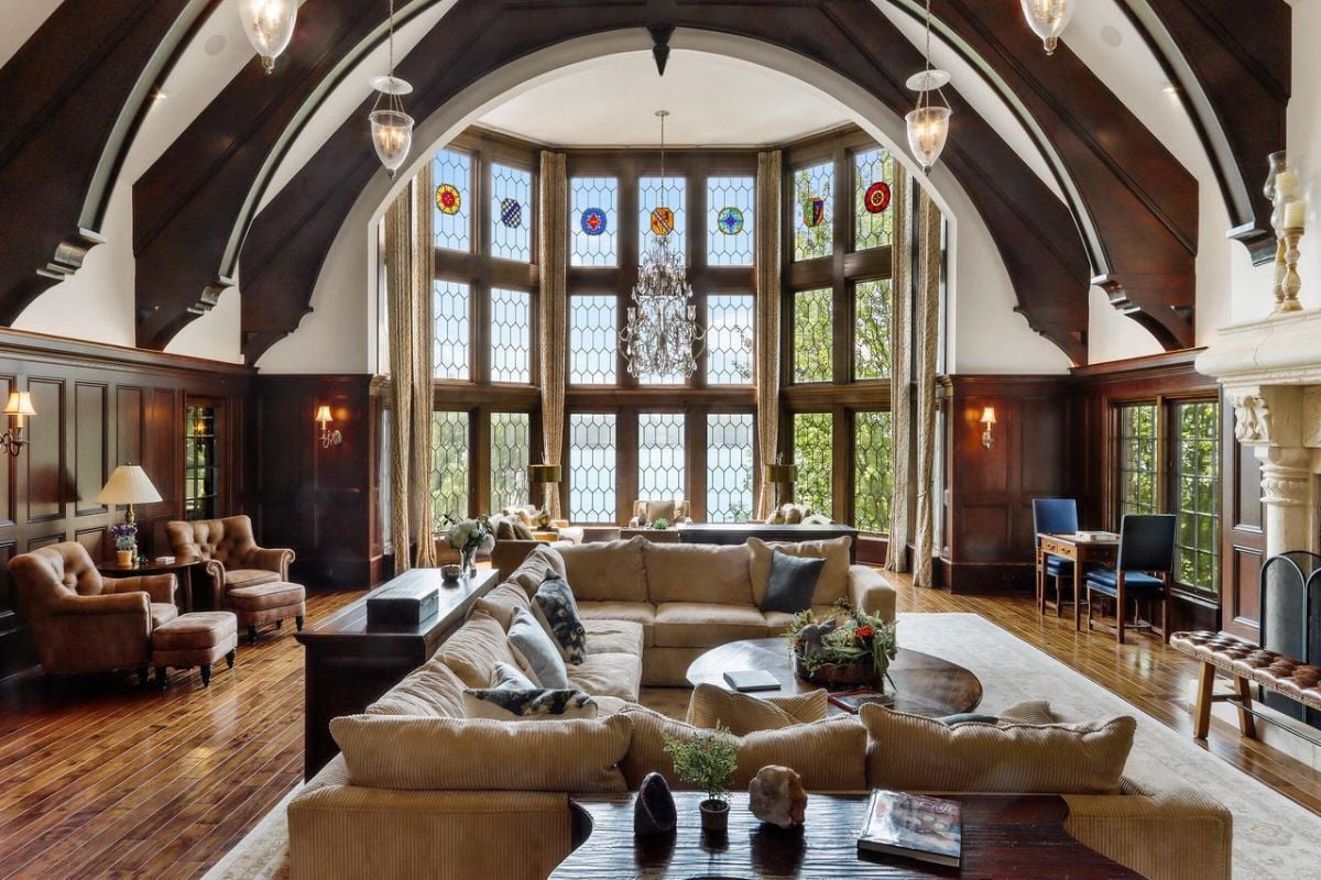 Living room with couches, wooden floors and large glass windows.