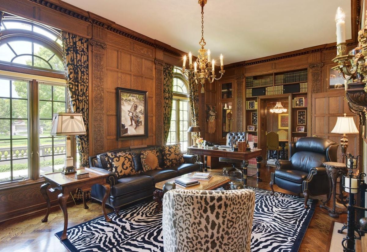 Home office with a chandelier, glass windows, couches, and a zebra print rug .