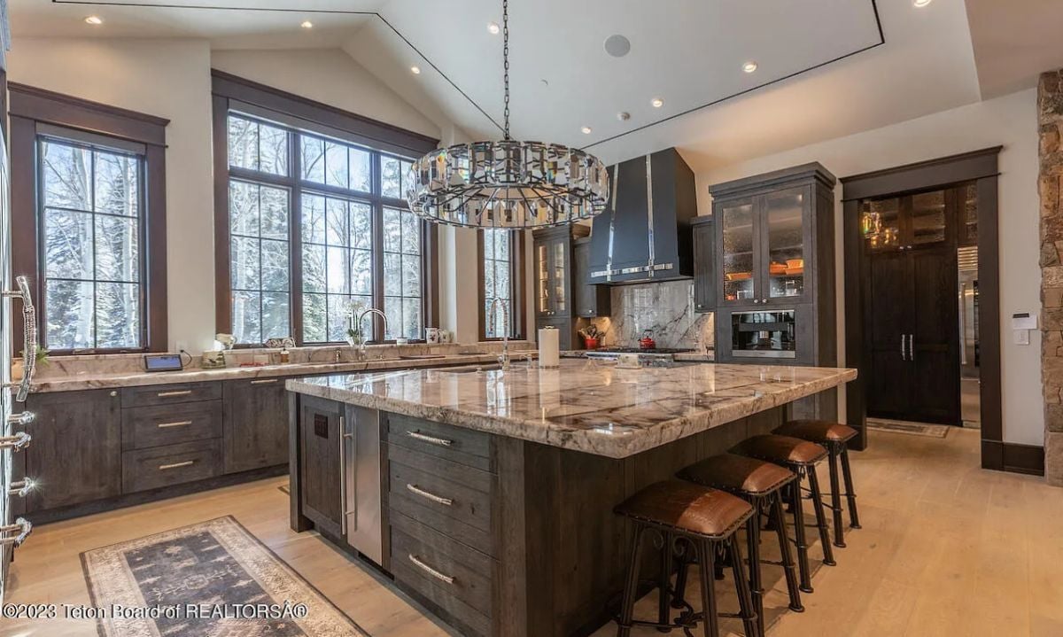 Kitchen with wood flooring, a chandelier, custom cabinetry, and a large island.