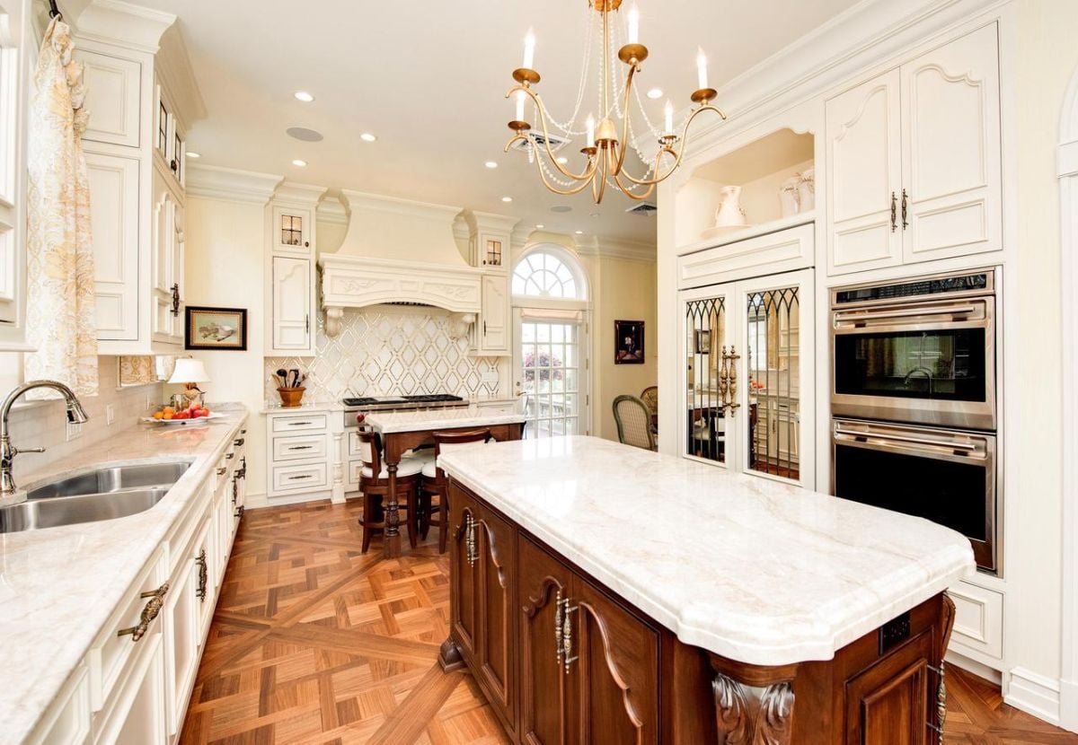 Kitchen with a chandelier, custom white cabinetry, and a large island.