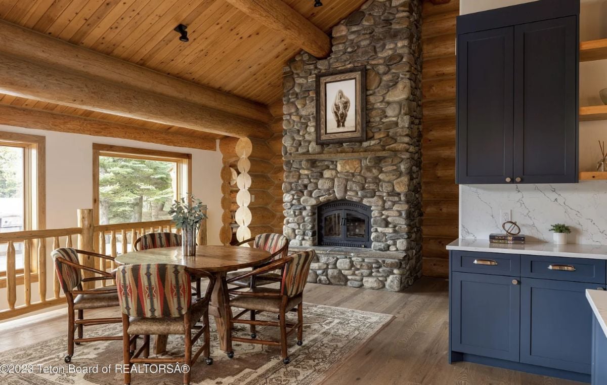 Breakfast area with a fireplace and a round wooden table.