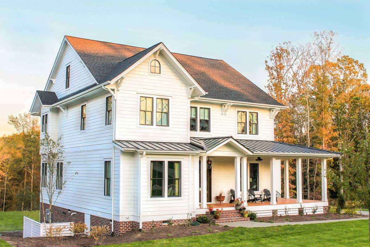 Front-left exterior view with horizontal siding, a brick base, and a covered entry porch.