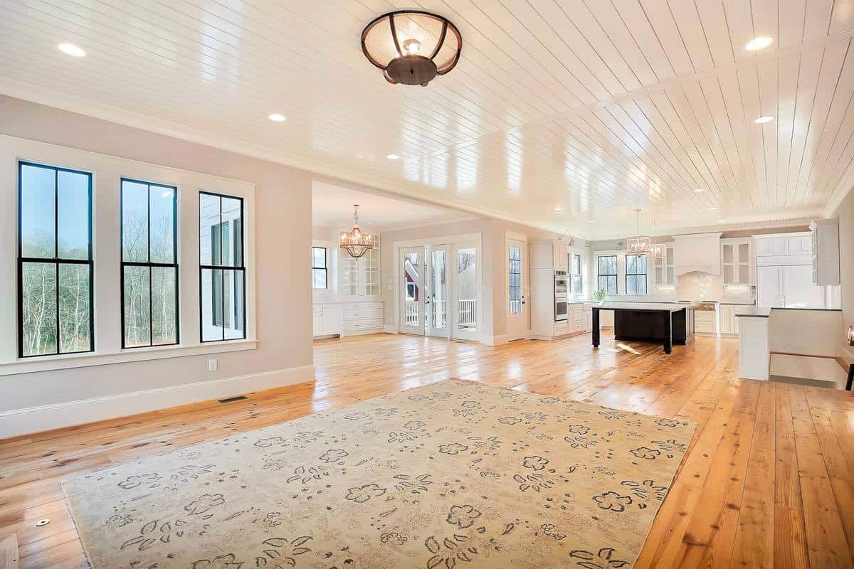 Great room with a large area rug and a white-paneled ceiling that spans through the kitchen.