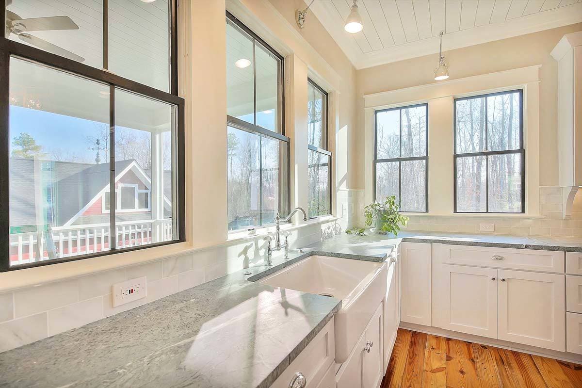 The kitchen includes a farmhouse sink and framed windows bringing natural light in.
