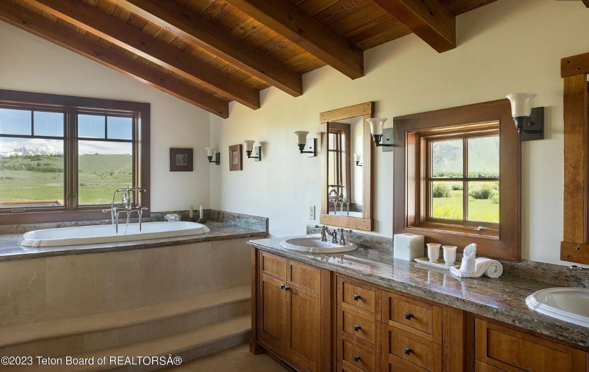 Bathroom with sinks, soaking tub, and custom cabinetry.