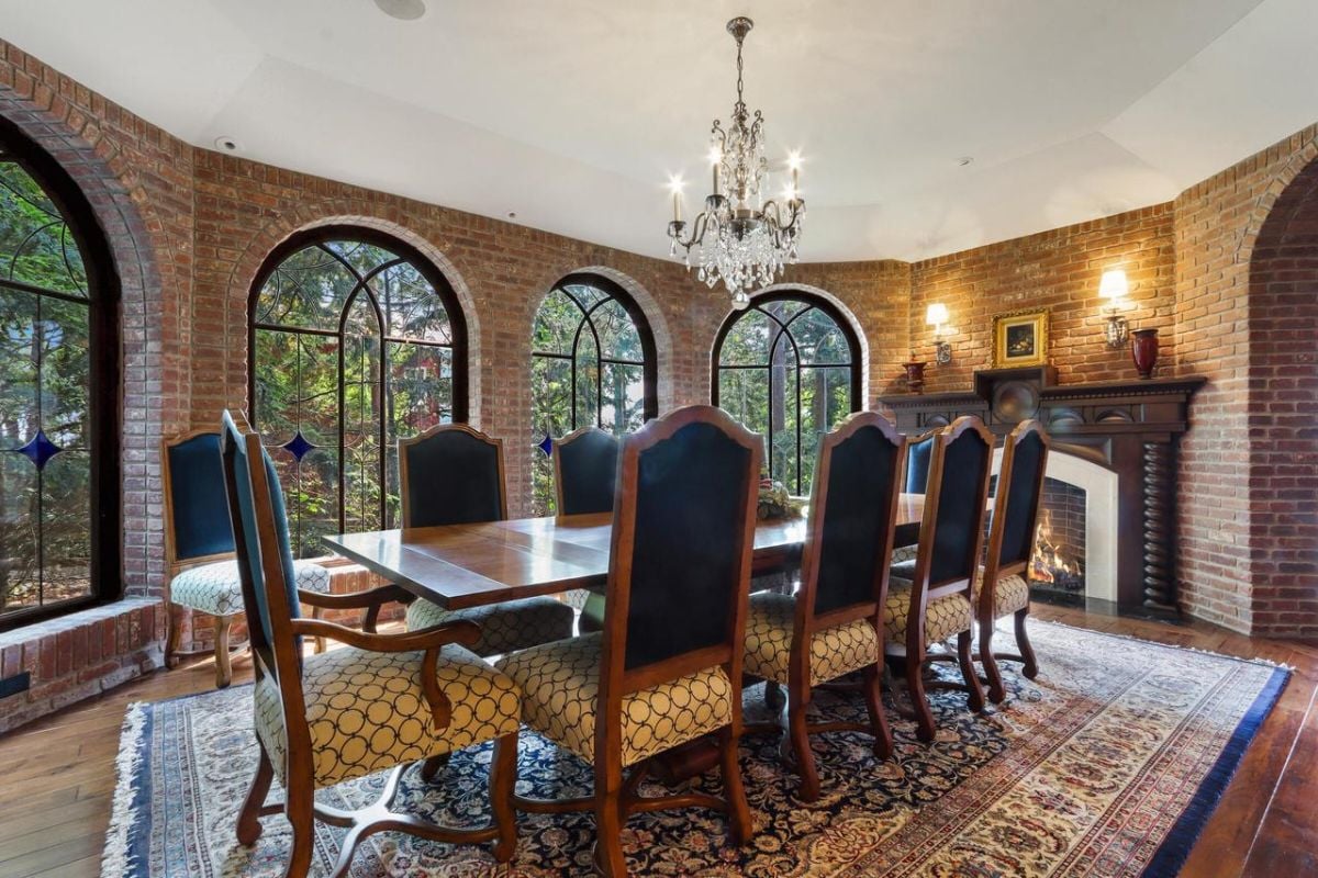 Dining room with a chandelier, a fireplace and glass windows.