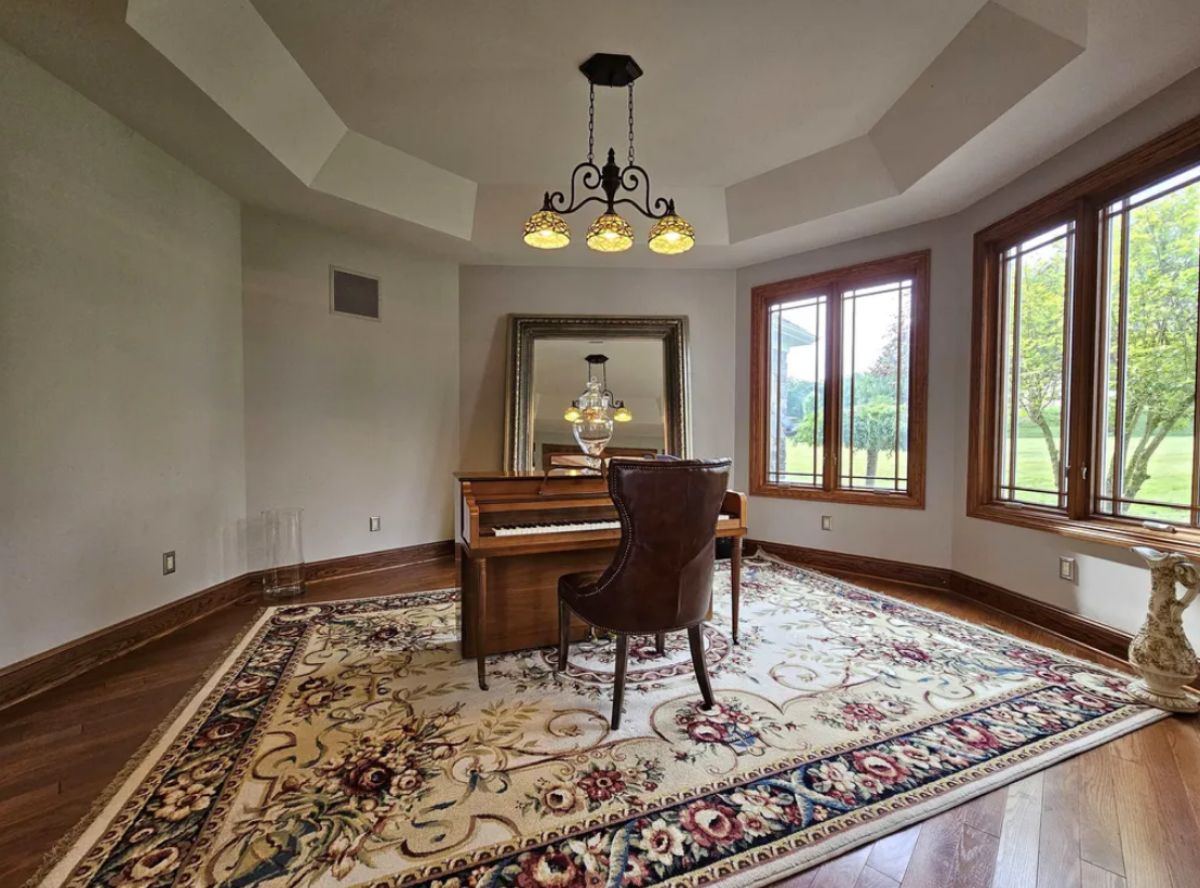 Piano room with wooden floors, a large rug, and large glass windows.