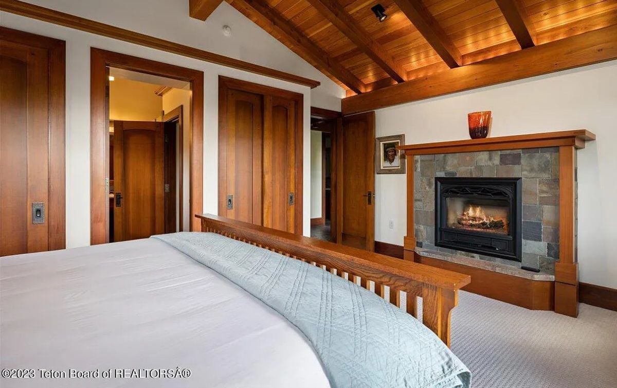 Bedroom with carpet flooring, vaulted ceiling and a fireplace.