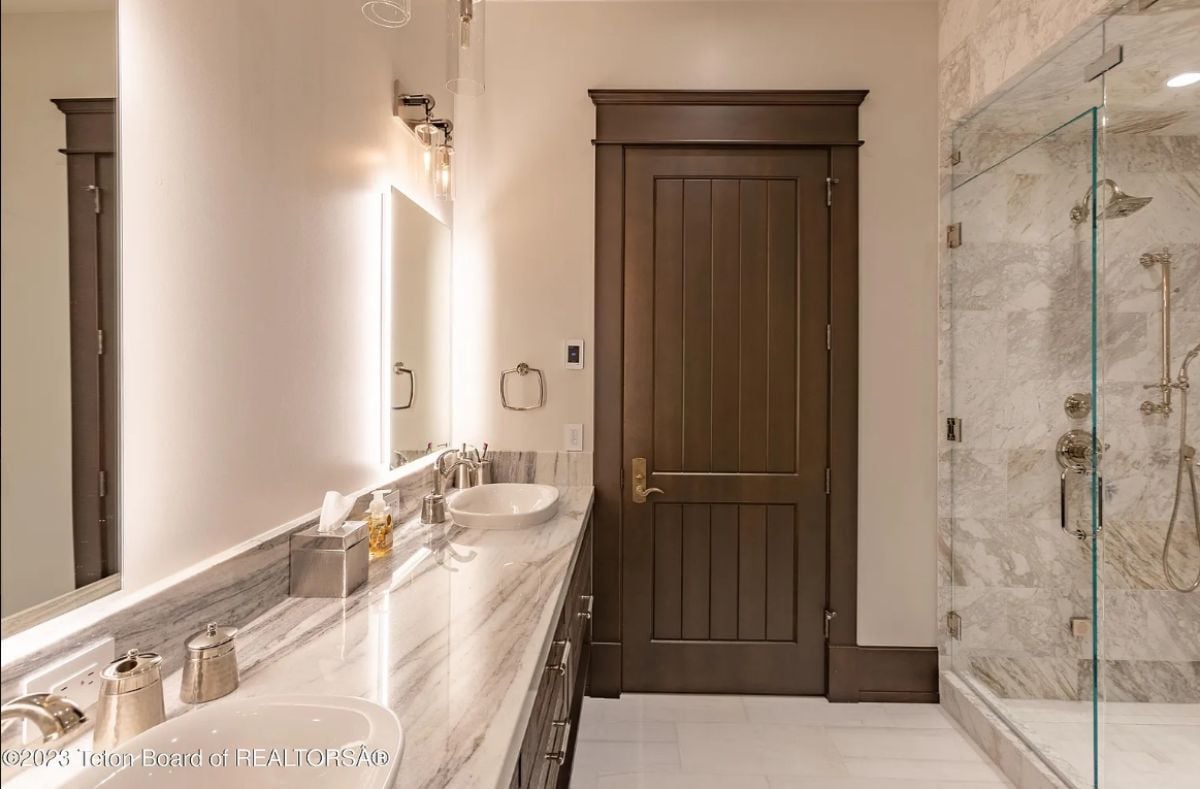 Bathroom with tile flooring, custom lighting, sinks, and a shower.