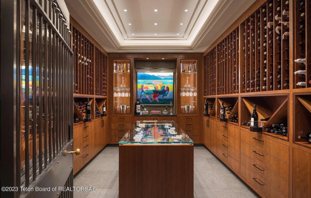 Wine cellar with wooden cabinets and glass shelves.