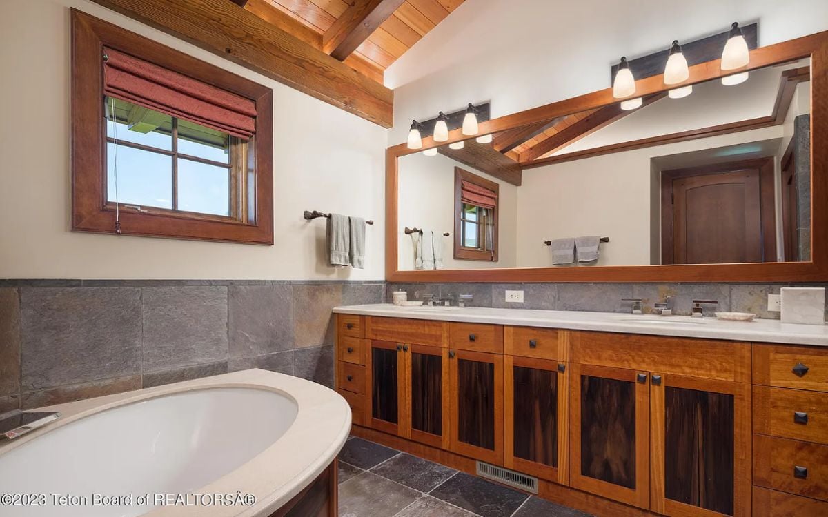 Bathroom with a soaking tub, sinks, and a large mirror.