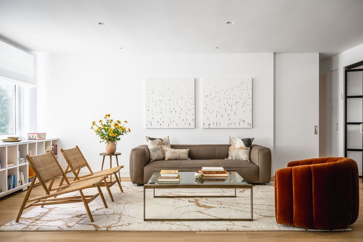 A living room with chairs, couch, center table and a glass window allows the sunlight to pass through