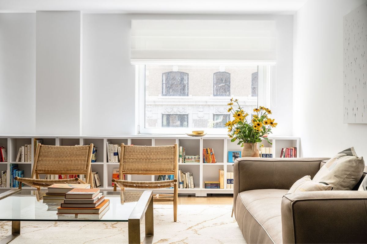 A living room with chairs, couch, center table and a glass window allows the sunlight to pass through