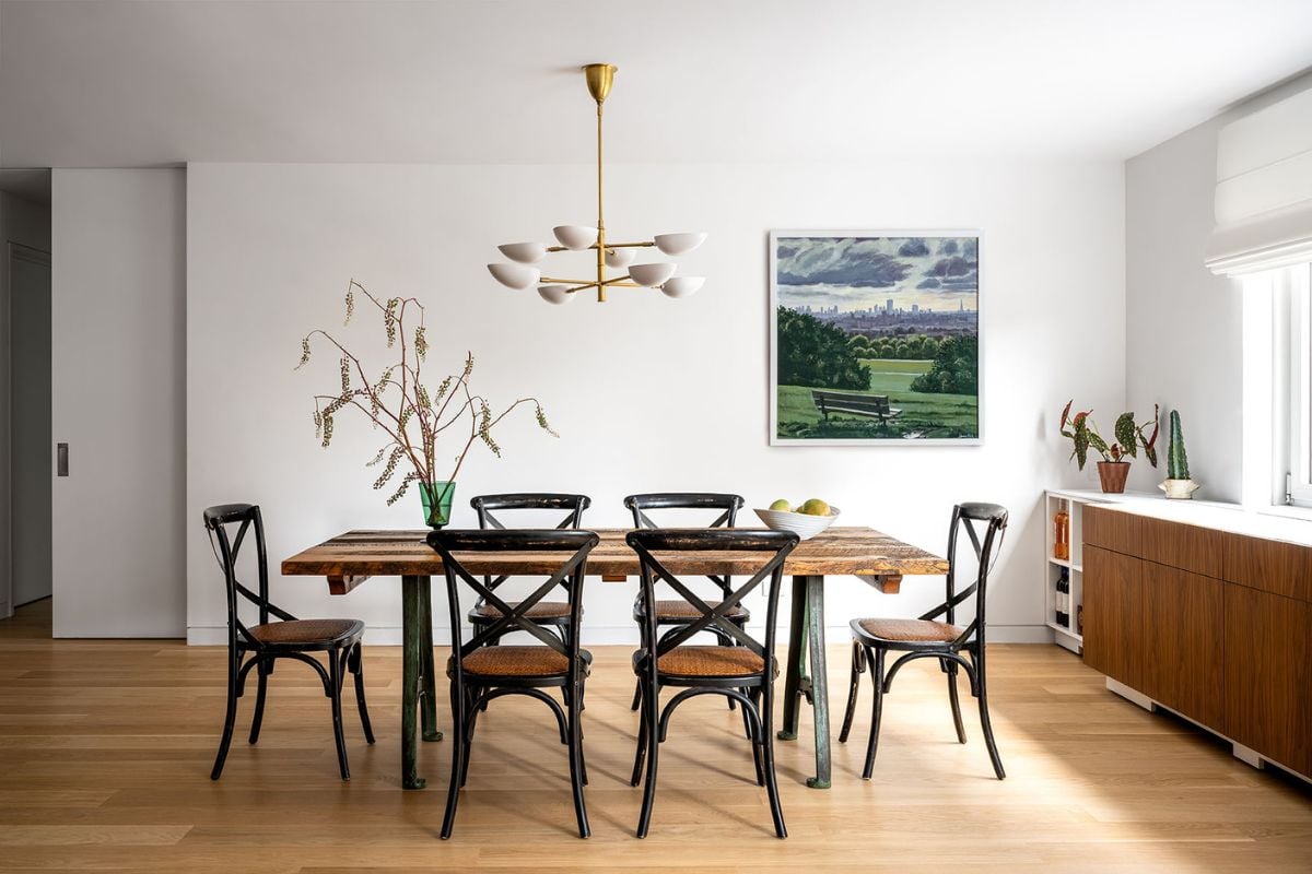 A dining room with wooden table, floors and white ceiling ad wall
