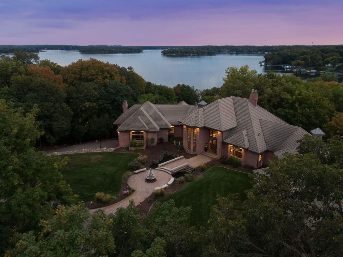 Aerial view of the mansion with a lake in the background.