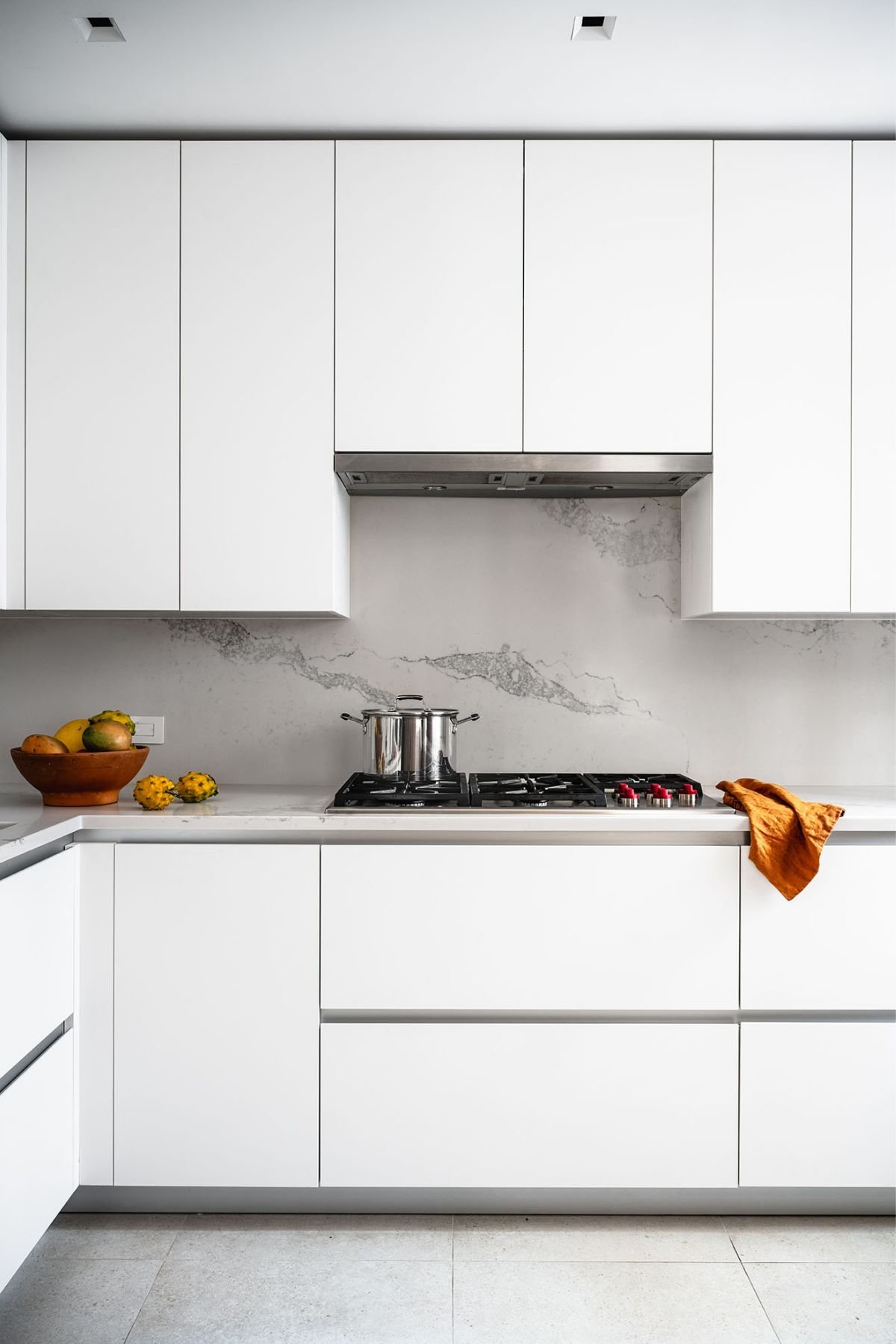 A white kitchen with white cabinets and a marble counter top