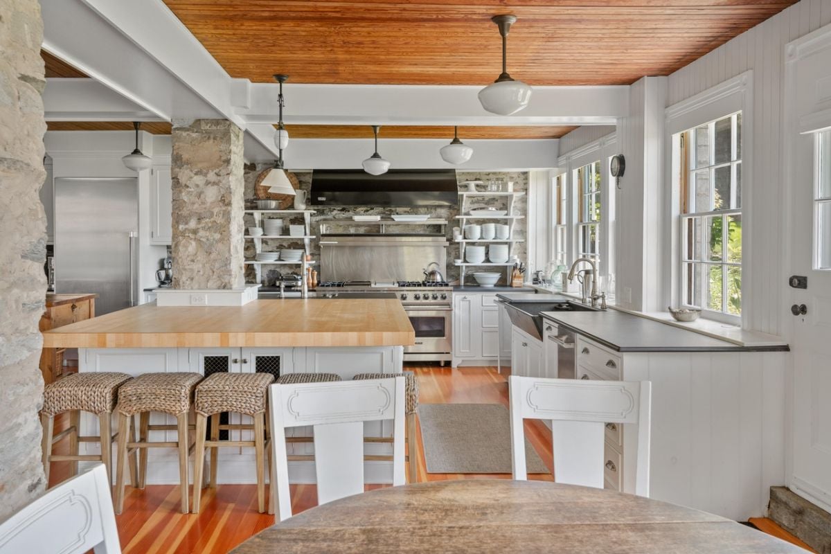 Kitchen with a large island, sink, stove, glass windows and a stove.