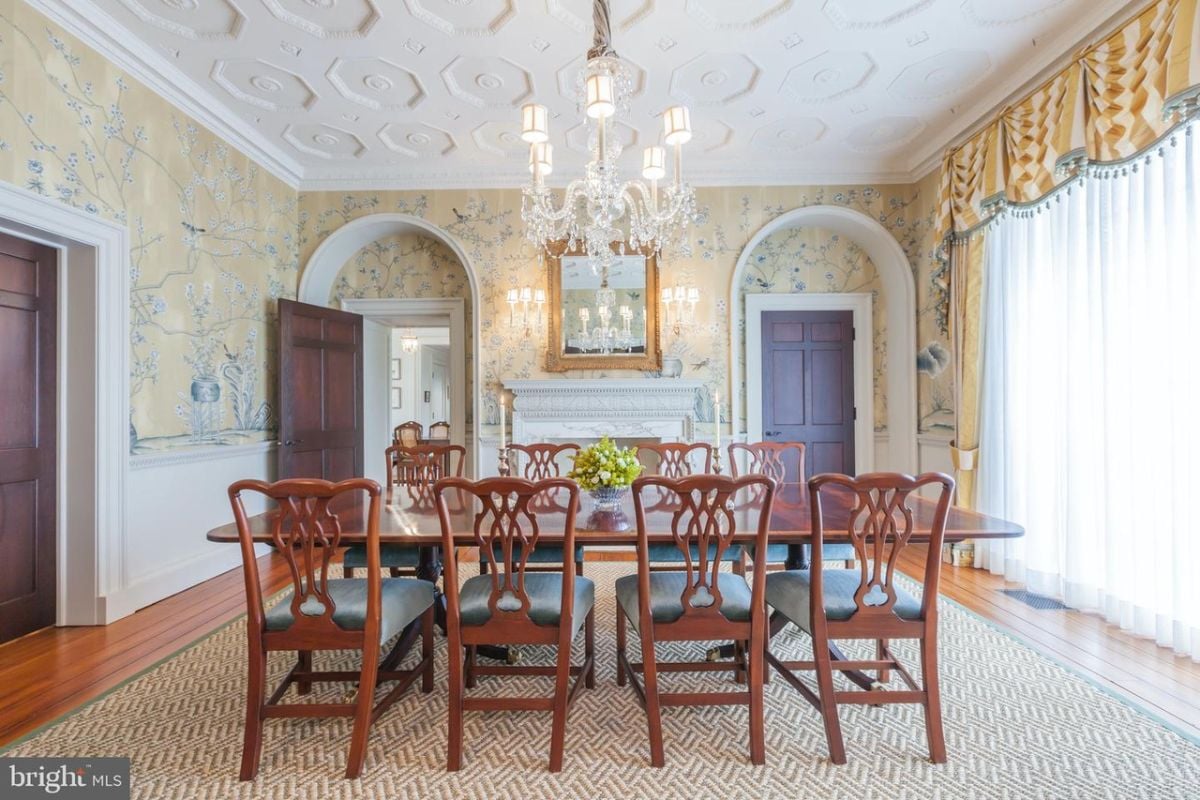 Dining room with a chandelier, wood flooring, a large rug, a wooden table and chairs.