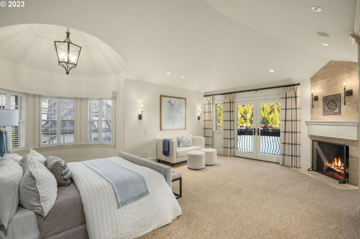 Bedroom with a bed, custom lights, glass windows, glass doors, carpet flooring and a fireplace.