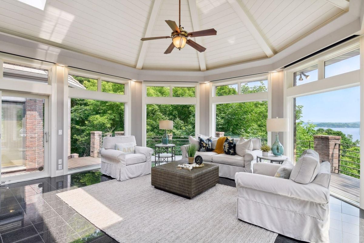 Living room with couches, a ceiling fan and glass wall windows.