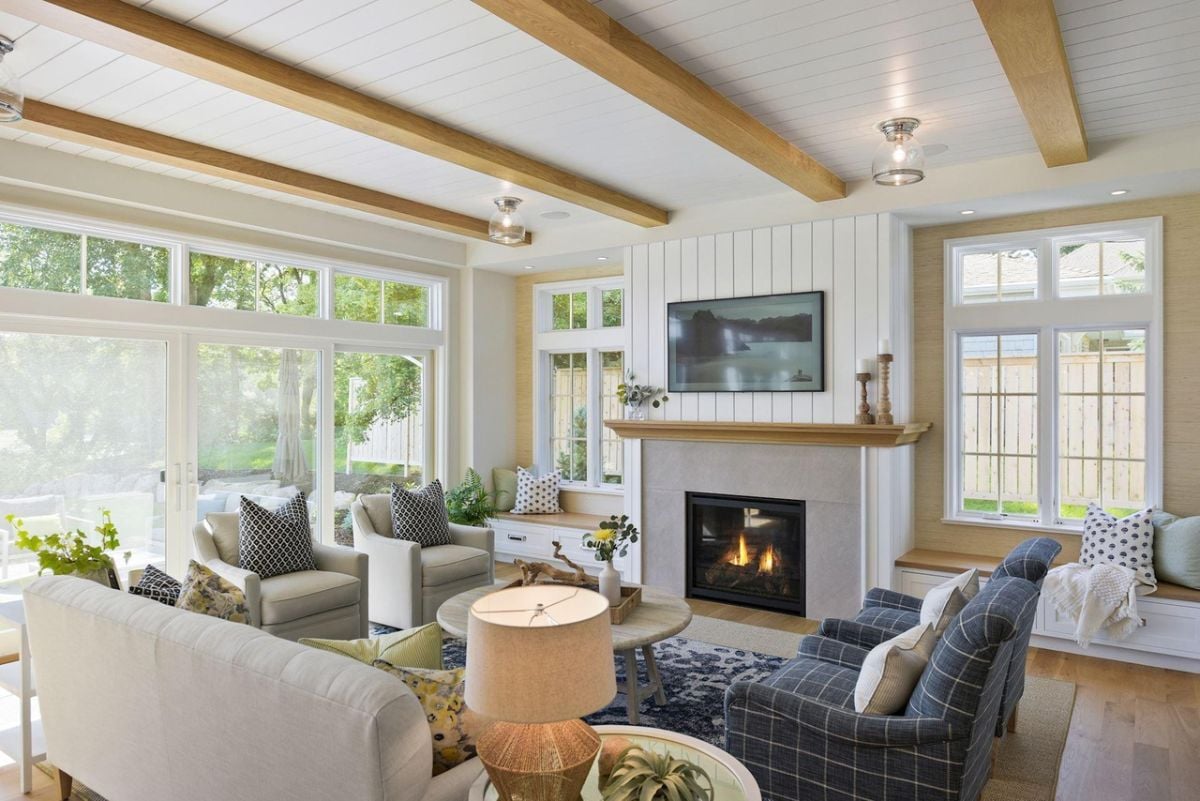 Living room with couches, glass windows, glass doors and a fireplace.